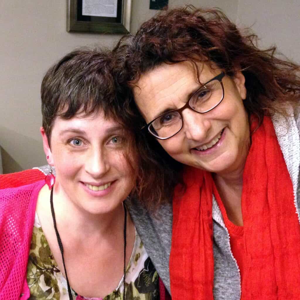 Sourcebooks CEO Dominique Raccah leans in close to author Susanna Kearsley, their heads touching affectionately. Both women are smiling at the camera.